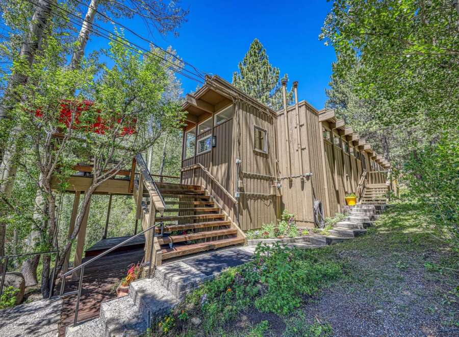 Nestled amidst lush greenery, this charming home offers a unique living experience with its elevated deck and multiple staircases leading to different levels.