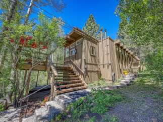 Nestled amidst lush greenery, this charming home offers a unique living experience with its elevated deck and multiple staircases leading to different levels.