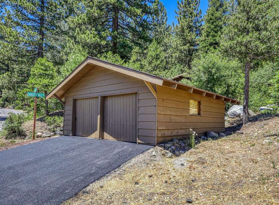 Discover this charming property featuring a rustic wooden garage with double doors, perfect for vehicle storage or a workshop.