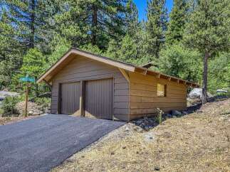 Discover this charming property featuring a rustic wooden garage with double doors, perfect for vehicle storage or a workshop.