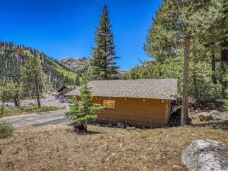 Nestled amidst towering pine trees and a picturesque mountain backdrop, this charming cabin offers a serene escape.