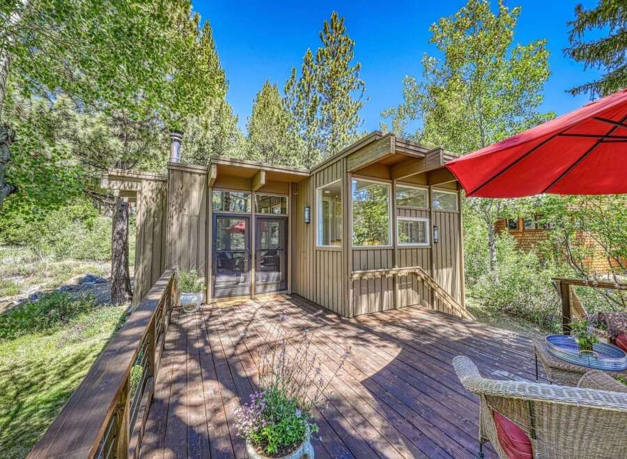 Enjoy the serene mountain lifestyle with this charming cabin featuring a spacious wooden deck perfect for outdoor relaxation.