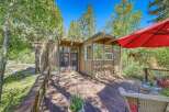 Enjoy the serene mountain lifestyle with this charming cabin featuring a spacious wooden deck perfect for outdoor relaxation.