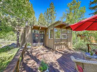 Enjoy the serene mountain lifestyle with this charming cabin featuring a spacious wooden deck perfect for outdoor relaxation.