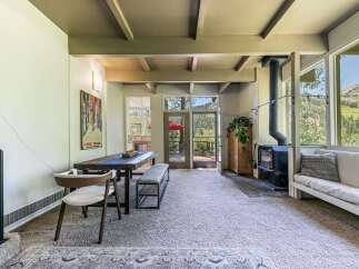 Experience breathtaking mountain views from this stunning property, featuring a cozy living area with a wood-burning stove and a spacious dining area perfect for gatherings.