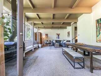 Experience rustic charm in this spacious living area featuring a cozy fireplace and exposed beam ceiling.
