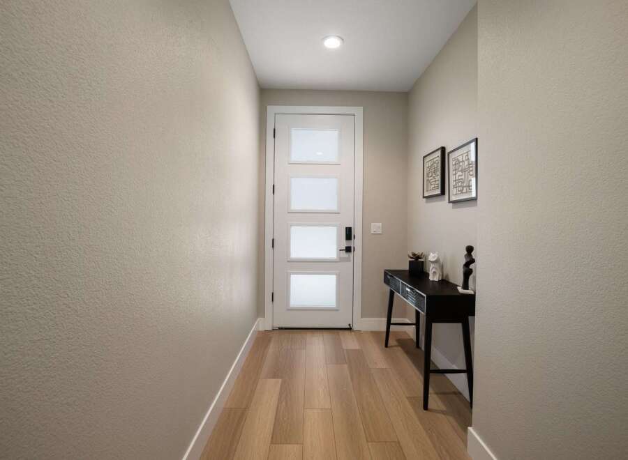 Step into this welcoming entryway featuring a modern white door with frosted glass panels, offering a glimpse of the natural light within.