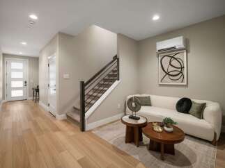 Step into this inviting living space featuring a stylish white sofa adorned with decorative pillows and a modern abstract artwork.