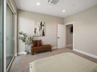 Experience modern comfort in this inviting bedroom, featuring a sleek leather bench with accent pillows and a contemporary abstract art piece.
