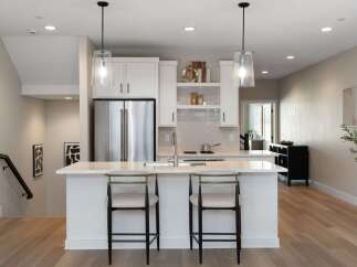 Experience modern living in this stunning kitchen featuring sleek white cabinetry, a spacious island with bar seating, and elegant pendant lighting.