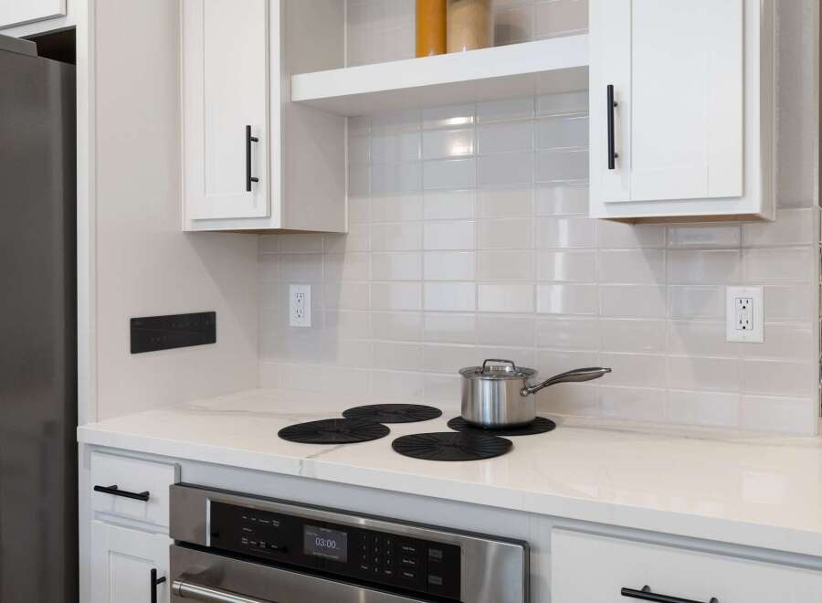 This modern kitchen features a sleek stainless steel oven and a smooth, white quartz countertop, perfect for meal preparation.