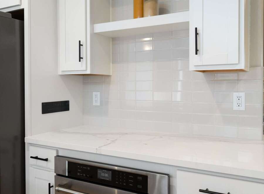 This modern kitchen features a sleek stainless steel oven and a smooth, white quartz countertop, perfect for meal preparation.
