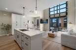 Experience modern living in this stunning open-concept space, featuring a sleek kitchen island with a waterfall countertop and a spacious living area.