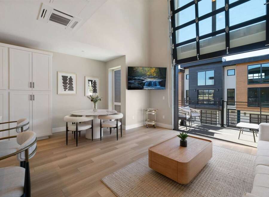 Experience modern living in this stunning apartment featuring a spacious open-concept living area with a sleek dining set and a comfortable seating arrangement.