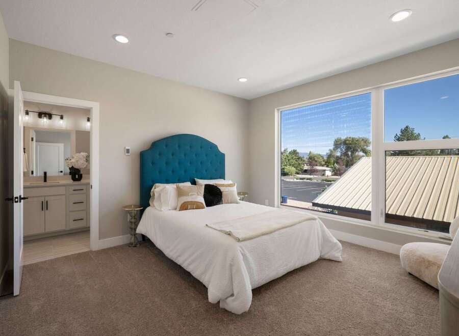 Experience modern comfort in this spacious bedroom featuring a luxurious tufted headboard and plush carpeting.