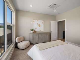 Experience modern comfort in this beautifully appointed bedroom, featuring a plush, oversized chair perfect for relaxation.