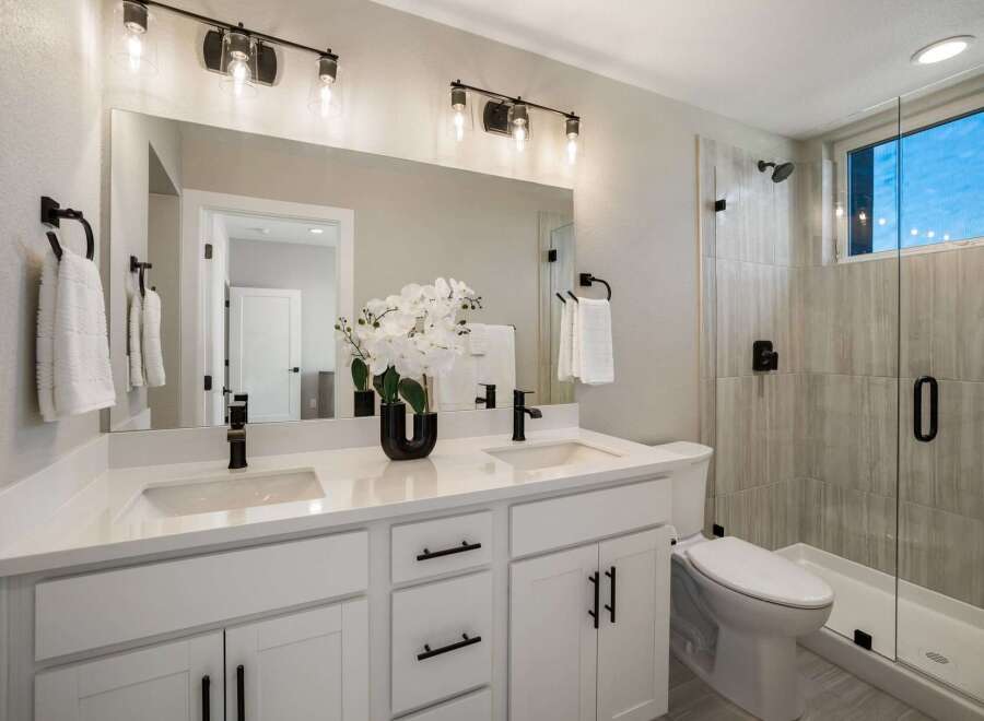 This modern bathroom features a spacious double vanity with sleek black fixtures and ample storage.