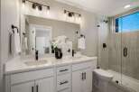 This modern bathroom features a spacious double vanity with sleek black fixtures and ample storage.