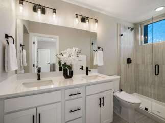 This modern bathroom features a spacious double vanity with sleek black fixtures and ample storage.
