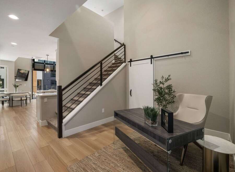 Step into a modern entryway featuring a sleek staircase with a dark metal railing and carpeted stairs.