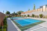 Enjoy outdoor recreation with this dedicated pickleball court, featuring a vibrant blue playing surface and a professional-grade net.