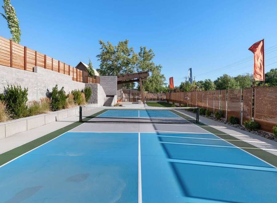 Enjoy outdoor recreation on this vibrant blue pickleball court, complete with a net and surrounding green and gray playing areas.