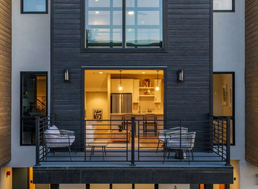 Experience modern living in this stunning townhouse featuring a sleek dark wood exterior and expansive windows.