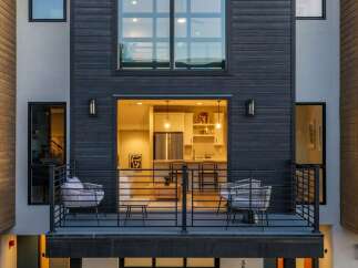 Experience modern living in this stunning townhouse featuring a sleek dark wood exterior and expansive windows.