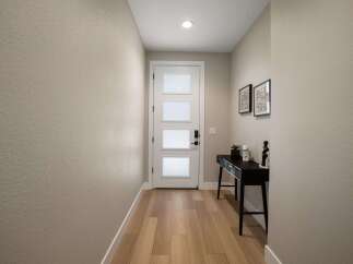 Step into this welcoming entryway featuring a modern white door with frosted glass panels, offering a glimpse of the natural light within.