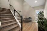 This modern entryway features a carpeted staircase with a sleek black metal railing, leading to an upstairs area.