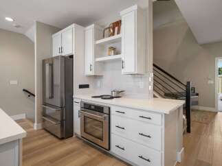 Discover this modern kitchen featuring sleek white cabinetry and stainless steel appliances, including a spacious refrigerator and a built-in oven.
