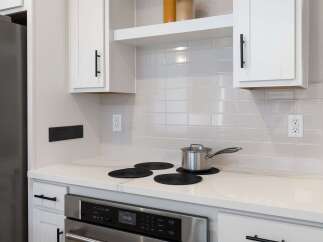 This modern kitchen features a sleek stainless steel oven and a smooth, white quartz countertop, perfect for meal preparation.