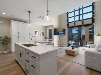 Experience modern living in this stunning open-concept space, featuring a sleek kitchen island with a waterfall countertop and a spacious living area.