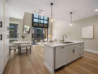 Experience modern living in this stunning open-concept space, featuring a sleek kitchen island with a waterfall countertop and a stylish dining area.