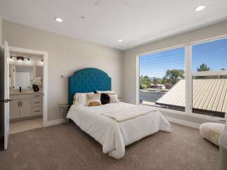 Experience modern comfort in this spacious bedroom featuring a luxurious tufted headboard and plush carpeting.