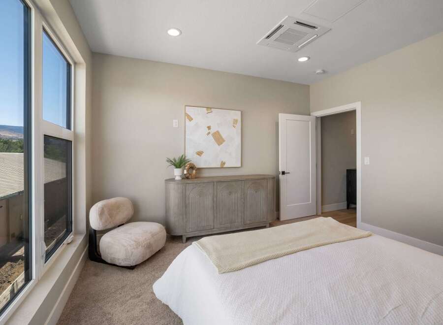 Experience modern comfort in this beautifully appointed bedroom, featuring a plush, oversized chair perfect for relaxation.