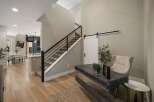 Step into a modern entryway featuring a sleek staircase with a dark metal railing and carpeted stairs.