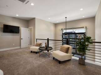 This loft space offers a cozy seating area with two plush armchairs and a modern coffee table, perfect for relaxation or conversation.