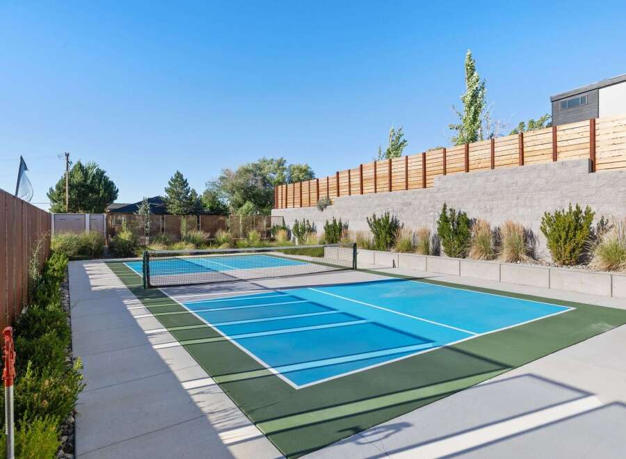 Enjoy outdoor recreation with this dedicated pickleball court, featuring a vibrant blue playing surface and a professional-grade net.