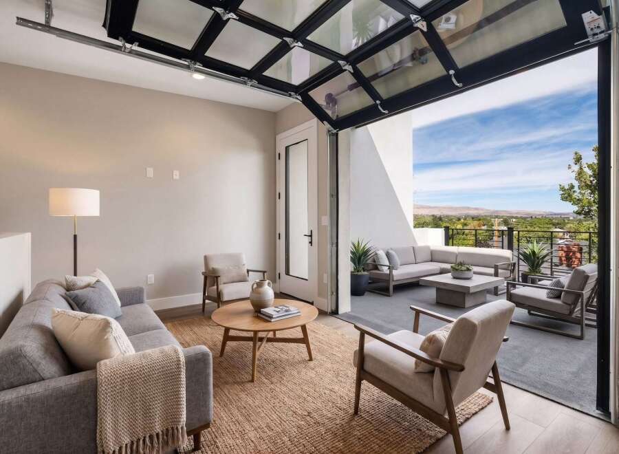Experience seamless indoor-outdoor living with this stunning modern living room featuring a unique glass garage door that opens to a spacious patio.