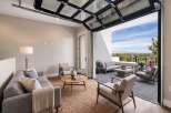 Experience seamless indoor-outdoor living with this stunning modern living room featuring a unique glass garage door that opens to a spacious patio.
