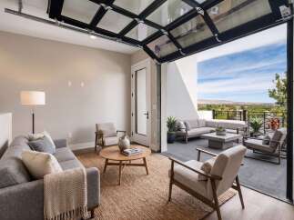 Experience seamless indoor-outdoor living with this stunning modern living room featuring a unique glass garage door that opens to a spacious patio.