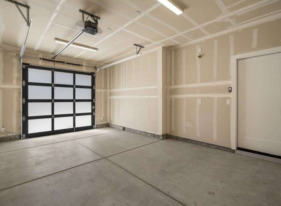 Discover this spacious garage featuring a modern glass and black panel garage door, perfect for illuminating your workspace.