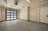Discover this spacious garage featuring a modern glass and black panel garage door, perfect for illuminating your workspace.