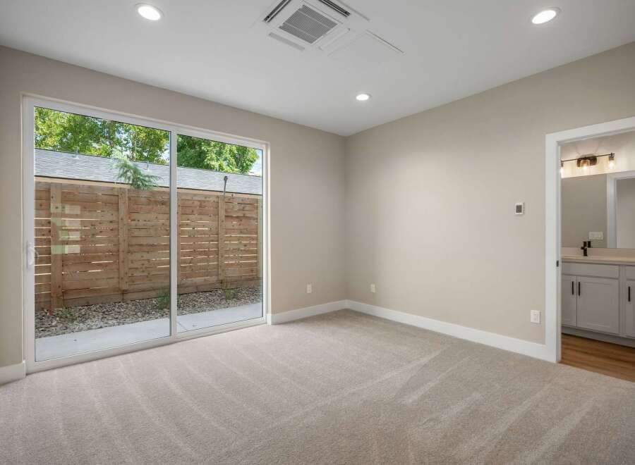 Step into this beautifully appointed bedroom featuring plush carpeting and a large sliding glass door that opens to a private outdoor space.