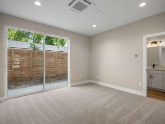 Step into this beautifully appointed bedroom featuring plush carpeting and a large sliding glass door that opens to a private outdoor space.