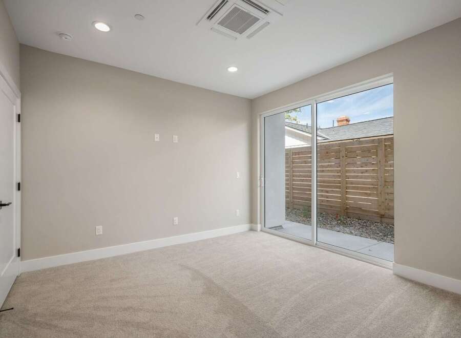 Step into this inviting room featuring plush carpeting and a modern sliding glass door that opens to a private outdoor space.