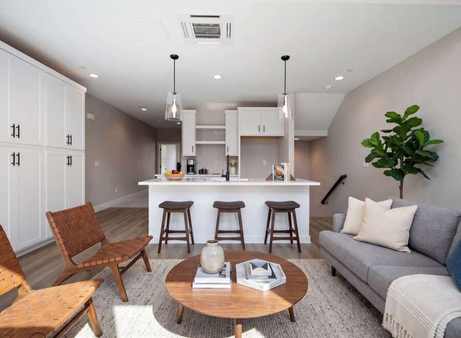 This modern living space features a sleek white kitchen island with bar stools, perfect for casual dining and entertaining.