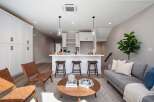 This modern living space features a sleek white kitchen island with bar stools, perfect for casual dining and entertaining.