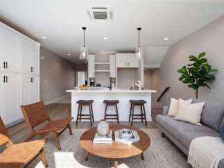 This modern living space features a sleek white kitchen island with bar stools, perfect for casual dining and entertaining.